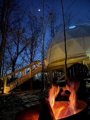 Fire crackling in the fire pit at dusk below the lit dome